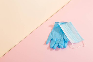 Sarı arka planda mavi tıbbi eldiven ve maske. Hastalıklara karşı koruma kavramı. Boşluğu kopyala.