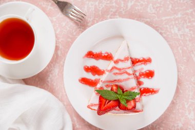 Tatlı kahvaltı, çay ve taze çilek ve nane aromalı leziz cheesecake, fırınlanmamış ev yapımı tarif, pembe taş masada. Boşluğu kopyala.