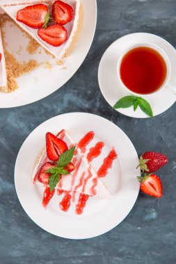 Tatlı kahvaltı, çay ve taze çilek ve nane aromalı lezzetli cheesecake, pişirilmemiş ev yapımı tarif, koyu mavi taş masa. Boşluğu kopyala.
