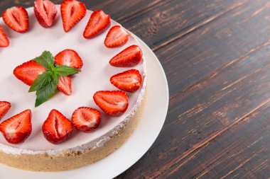 Taze çilek ve nane ile nefis cheesecake, ahşap bir masada pişirmeden ev yapımı tarifi.