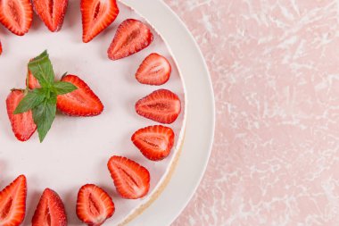 Tatlı kahvaltı, taze çilek ve nane aromalı lezzetli cheesecake, pişirilmemiş ev yapımı tarif, pembe taş masada. Boşluğu kopyala.