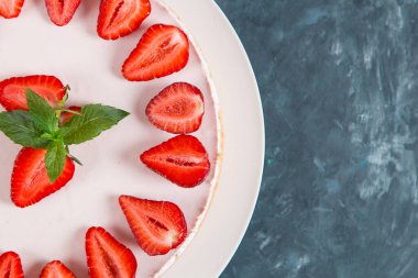 Tatlı kahvaltı, taze çilek ve nane ile nefis cheesecake, pişirilmemiş ev yapımı tarif, koyu mavi taş masada. Boşluğu kopyala.