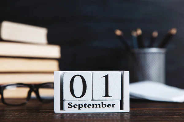 Books, calendar, notebooks, pencils, glasses and cup of coffee, against the background of a chalkboard. Concept for knowledge day. Copy space.