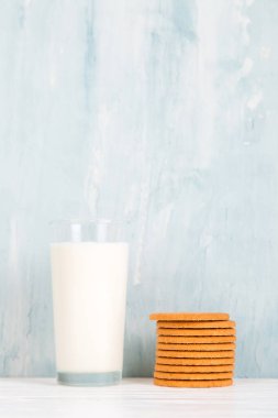 Masada bir bardak süt ve kurabiye, mavi arka planda, minimalizm. Boşluğu kopyala.