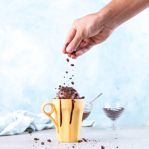 Шоколадное Коричневое Мороженое Обычной Желтой Кружке Синем Фоне Рука Выливается — стоковое фото