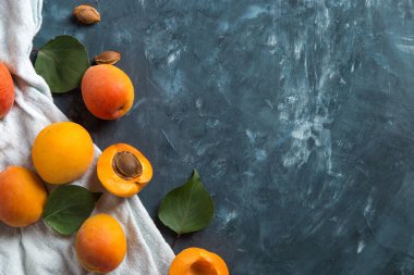Olgun taze kayısılar ve koyu mavi beton bir masada bir havlu. Üst görünüm, düz görünüm, kopyalama alanı.