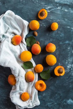 Olgun taze kayısılar ve koyu mavi beton bir masada bir havlu. Üst görünüm, düz görünüm, kopyalama alanı.