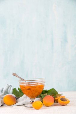 Cam tabakta kayısı reçeli ve beyaz bir masada olgun kayısılar..