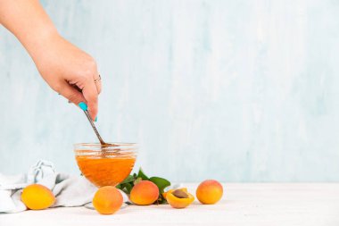 Cam tabakta kayısı reçeli ve beyaz bir masada olgun kayısılar..