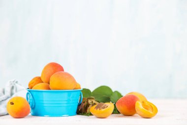 Beyaz masadaki mavi vazoda sulu, olgun kayısılar..