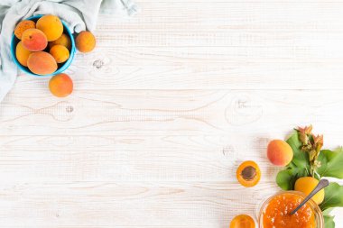 Cam tabakta kayısı reçeli ve beyaz bir masada olgun kayısılar..