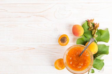 Cam tabakta kayısı reçeli ve beyaz bir masada olgun kayısılar..