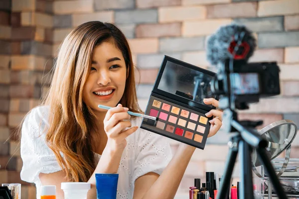 Encantadora chica asiática grabando vlog. Blogger de belleza presentando cosméticos de maquillaje delante de la cámara — Foto de Stock