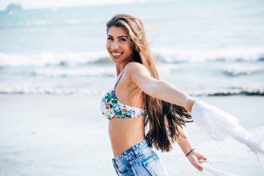 Beyaz kaşkollu tropikal yaz plaj rüzgar üfleme ile poz genç çekici ve güzel beyaz bir kadın 