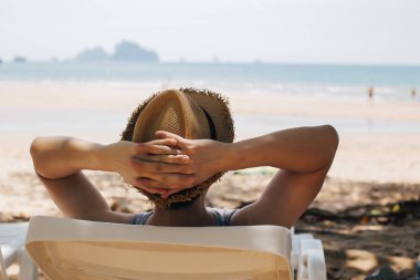 Yakın çekim Genç erkek gezgin rahatlatıcı ve plaj sandalyede oturan-yaz tatil kavramı.