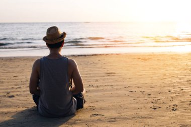 Gün batımı sırasında silüet üzerinde açık havada tropikal deniz plajında Zen meditasyon pratik genç erkek seyahat Backpacker-sakin ve huzur Yoga kavramı poz.