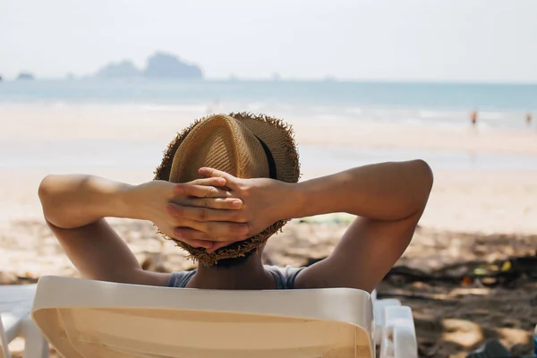 Närbild av unga manliga resenären avkopplande och sitter på stranden stol-sommar semester koncept. — Stockfoto