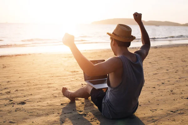 Un jeune homme d'affaires lève la main pour réussir sur la plage tropicale estivale - cela indique la liberté comme la liberté financière ou le concept de travail à distance . — Photo
