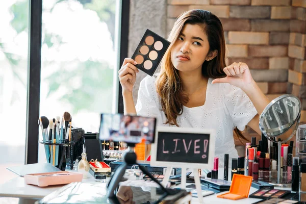 Enojada mujer asiática sosteniendo sombras de ojos y mostrando el pulgar hacia abajo — Foto de Stock