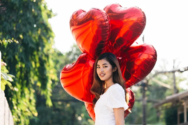 Чувственная азиатка с воздушными шарами, смотрящая в сторону — стоковое фото