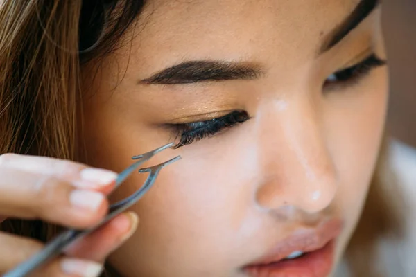 Mujer asiática colocando pestañas decorativas en el ojo — Foto de Stock