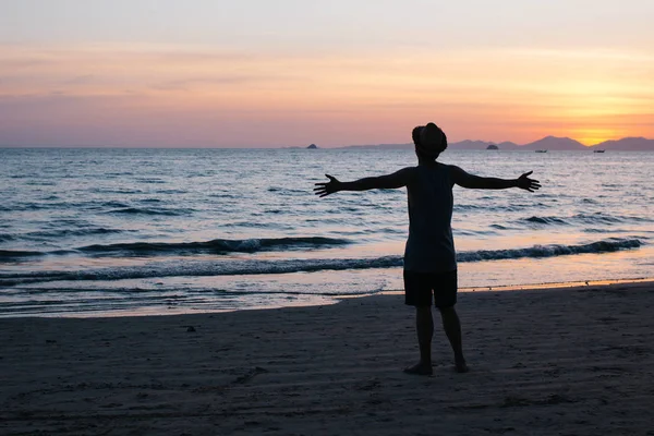 Oigenkännlig man med utsträckta armar nära havet — Stockfoto