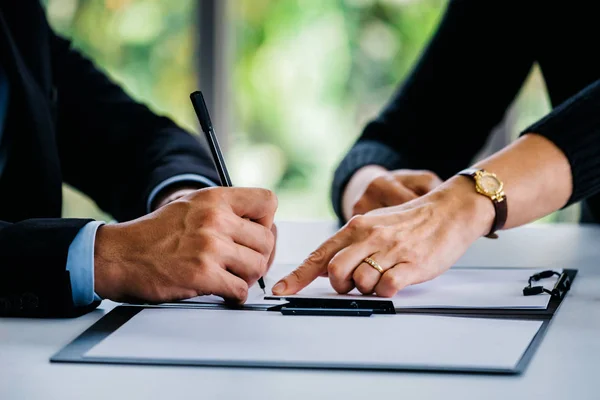 Man signing documents near woman at table — Stock Photo, Image