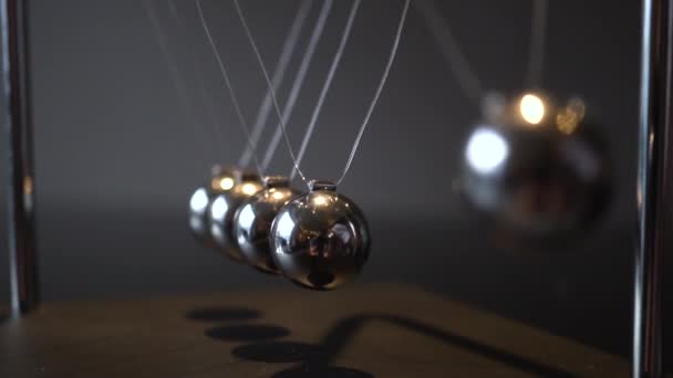 Видеоклип крупным планом металлической колыбели Ньютона, качающейся на сером фоне — стоковое видео