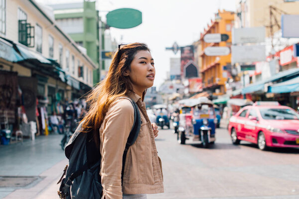 Young Asian female tourist backpacker walking on Khao San road during traveling to Thailand