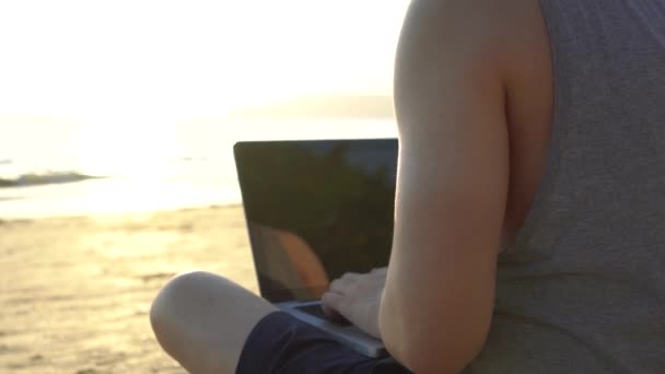Анонімний фрілансер, що використовує ноутбук біля моря — стокове відео