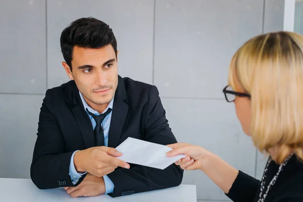 Young man taking paper from adult blond woman — Stock Photo, Image