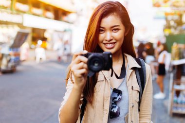 Genç kadın bir kamera tutarak ve Tayland fotoğraf çekmek