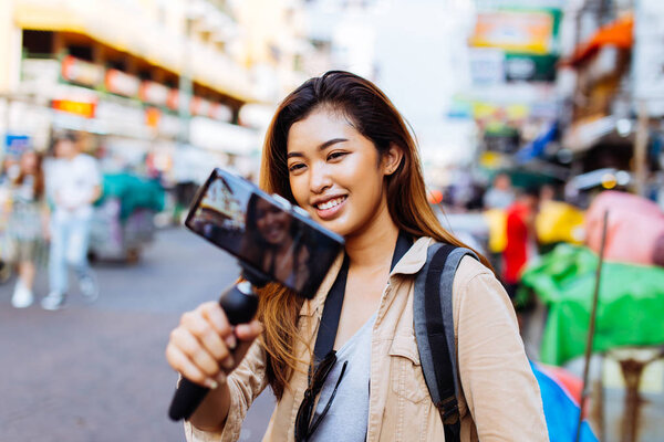 Young female tourist holding a gimbal with smartphone and recording videos. Travel blogger and vlogger concept