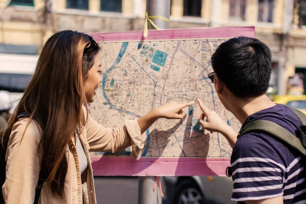 Νεαρό ζευγάρι τουρίστρια κοιτάζοντας τον χάρτη της πόλης και κατευθύνσεις μαζί — Φωτογραφία Αρχείου