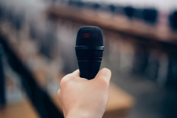 Hands of speaker holding a microphone for speech presentation in conference seminar room