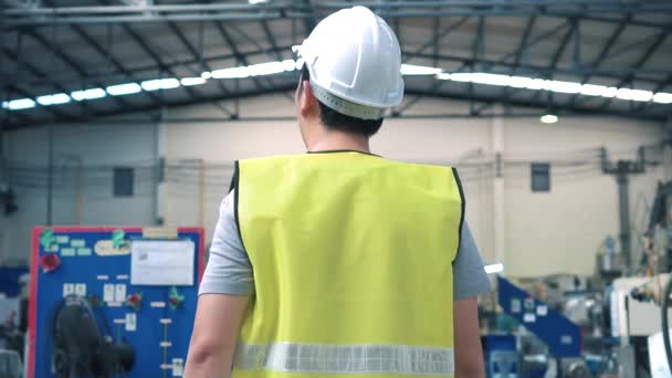 Ouvrier d'usine avec casque de sécurité marchant à travers les installations industrielles — Video