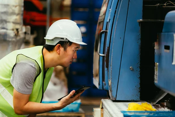 Young Asian engineer inspecting machine in factory — Stock Photo, Image