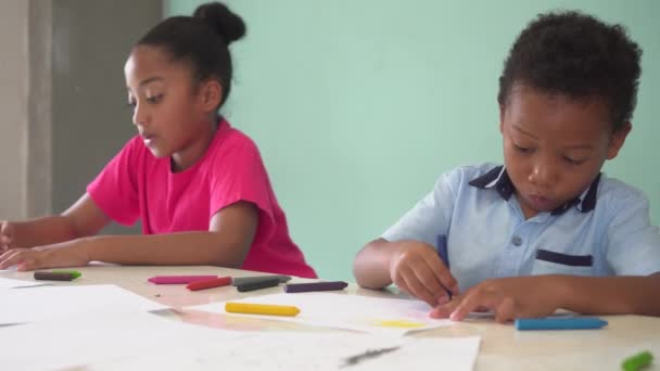Niños afroamericanos aprendiendo a dibujar con crayón en la mesa — Vídeos de Stock