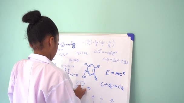 African American Girl in Lab vacht tekenen mathematische en Science formules op wit bord — Stockvideo