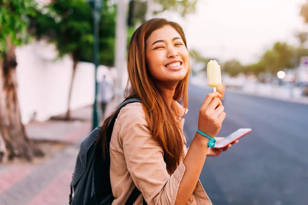路上でアイスクリームと電話で幸せな民族の女性 — ストック写真