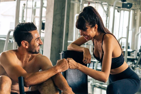 Two young happy fitness buddies doing fist bump in gym