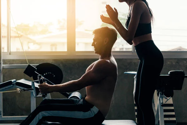 Junger kaukasischer Mann in einem Fitnessstudio, trainiert hart und zieht Gewichte in sitzendem Seilzuggerät — Stockfoto