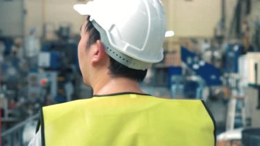 Endüstriyel tesislerde yürüyen güvenlik sert şapkalı fabrika işçisi