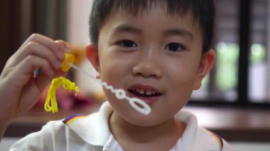 Küçük çocuk kabarcıklar üfleme ve evde gülümseyen