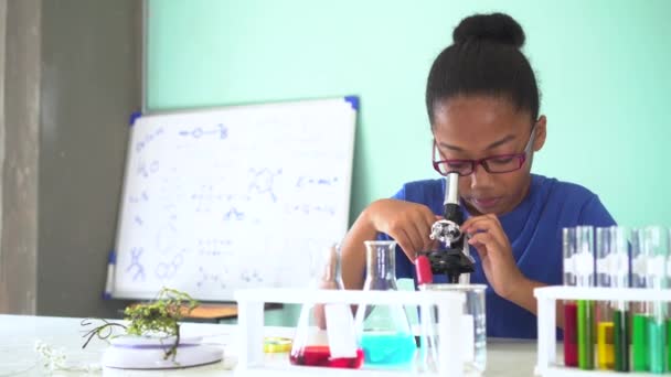 Niño afroamericano joven usando microscopio en laboratorio — Vídeos de Stock