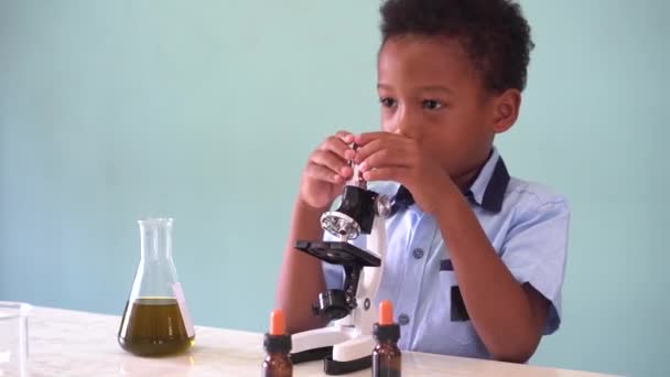 Young African American kid using microscope in lab — Stock video