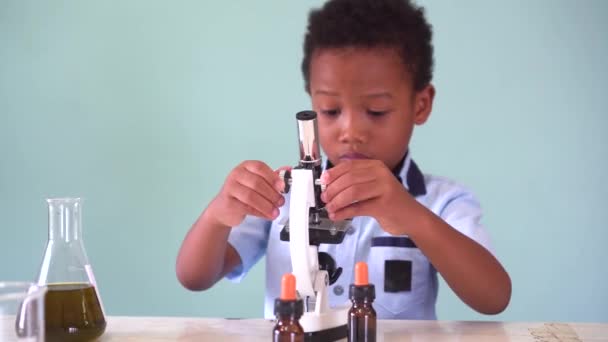 Niño afroamericano joven usando microscopio en laboratorio — Vídeos de Stock