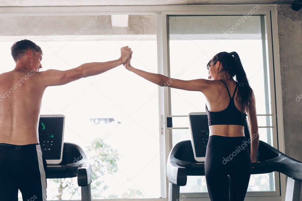 Fitness buddies clasping hands during treadmill workout
