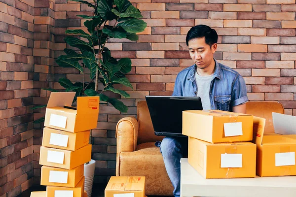 Evde kutular paketleri ile laptop kullanarak Asya erkek iş girişimci