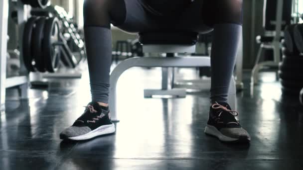 Mujer joven en ropa deportiva haciendo ejercicio de bíceps de rizo de concentración de mancuerna sentada en el gimnasio . — Vídeos de Stock